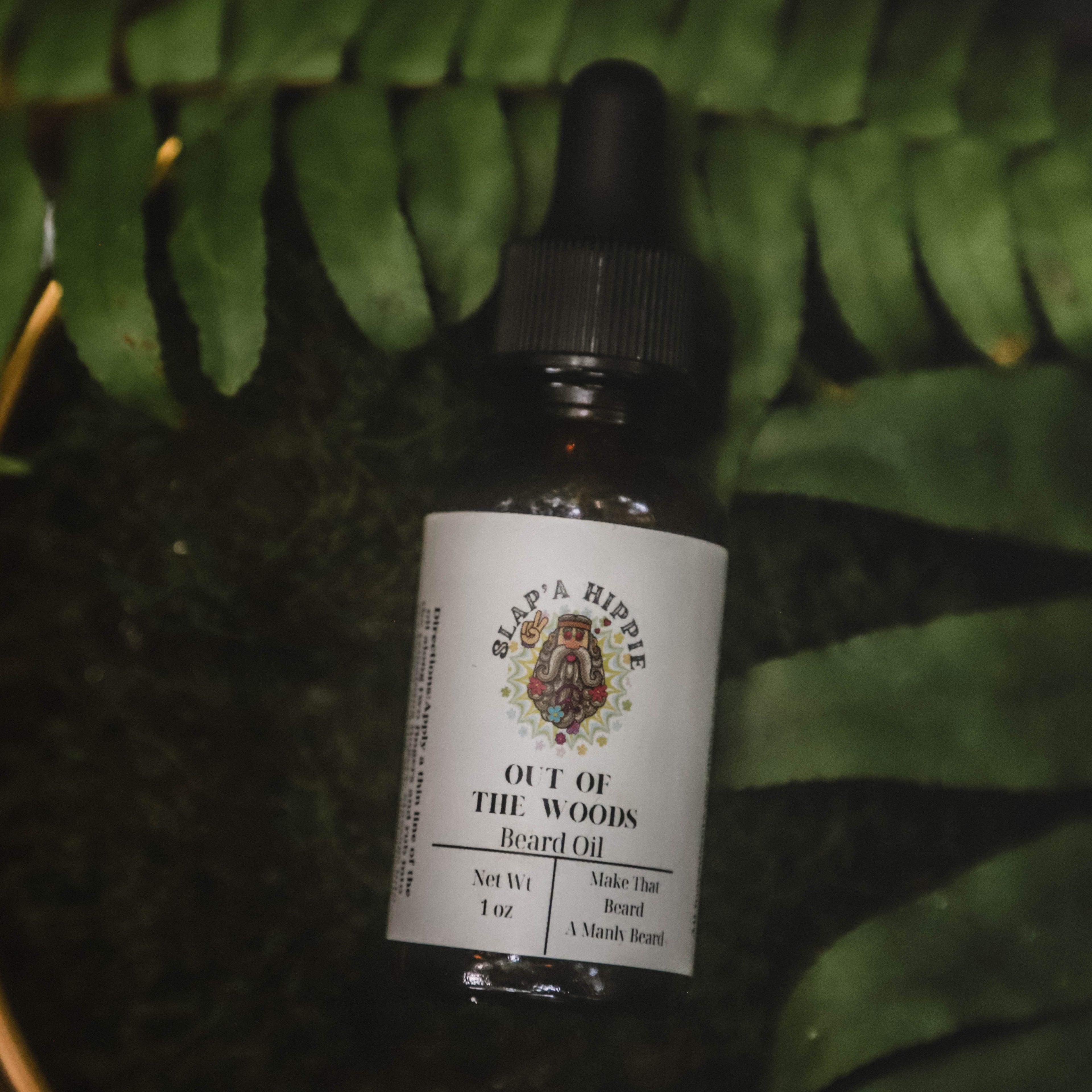 Bottle of 'Out of the Woods' beard oil with a dropper against a green leafy background