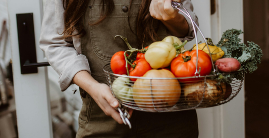 Woman holding a metal basket full of fresh produce