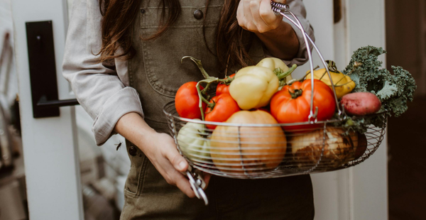 Woman holding a metal basket full of fresh produce